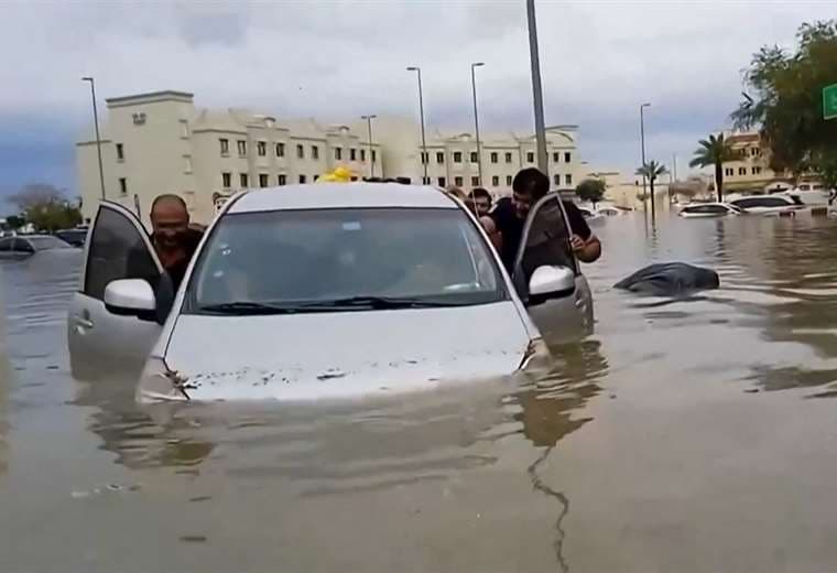 Personas empujan un automóvil varado por una calle inundada en Dubái /Video: AFPTV