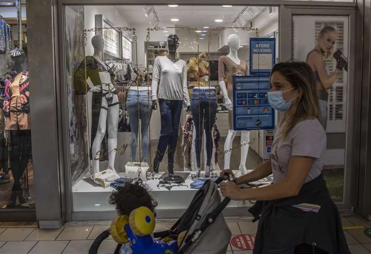 Una mujer camina dentro de un centro comercial recientemente reabierto en Santiago. Foto AFP