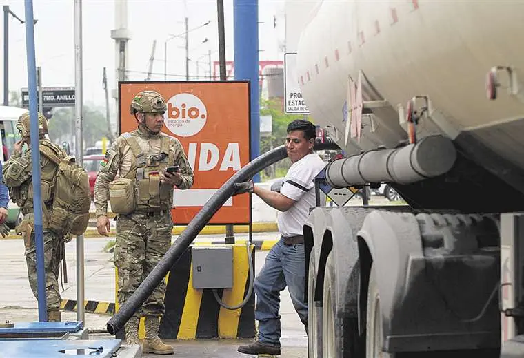 El operario de un surtidor descarga combustible con vigilancia militar /R. Montero