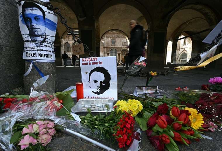 Flores junto a carteles del fallecido líder opositor ruso Alexéi Navalni en Milán / AFP