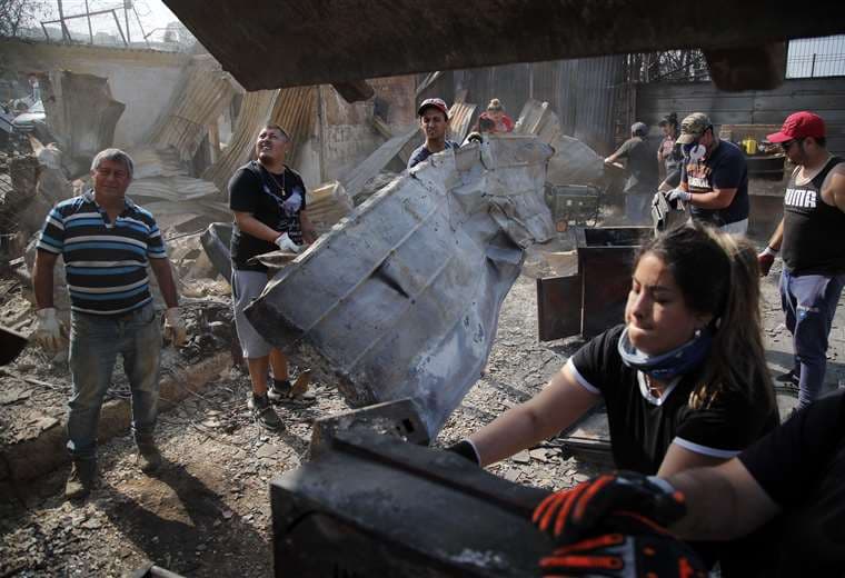 Residentes retiran escombros de casas quemadas después de los incendios forestales / AFP