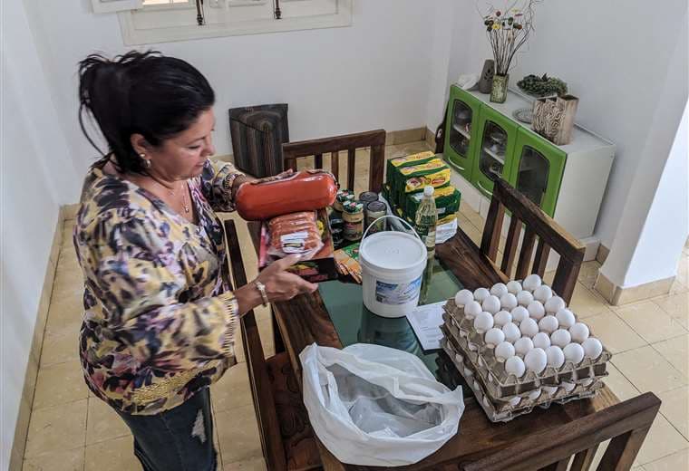 María Páez, de 59 años, organiza la comida que sus hijos le enviaron desde Miami / AFP