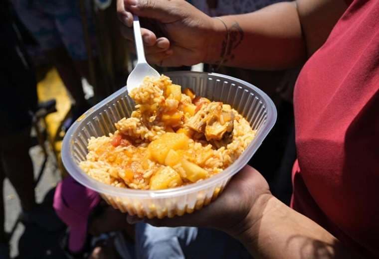 Una voluntaria muestra comida servida en un comedor comunitario / AFP