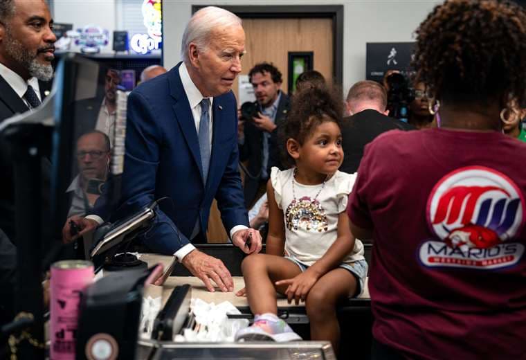 El presidente Joe Biden saluda a una niña durante una visita en una tienda / AFP