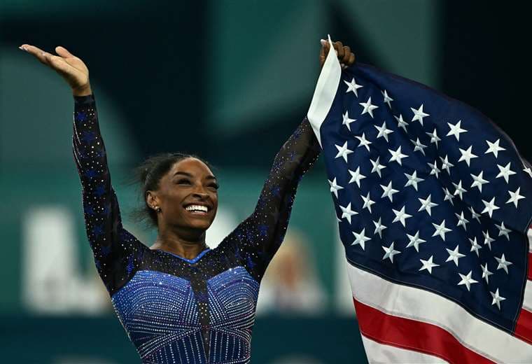 Biles festeja su victoria con la bandera de Estados Unidos.