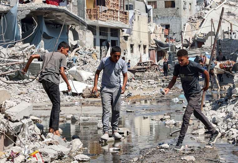 Jóvenes caminan en medio de escombros en zonas bombardeadas en Gaza/AFP