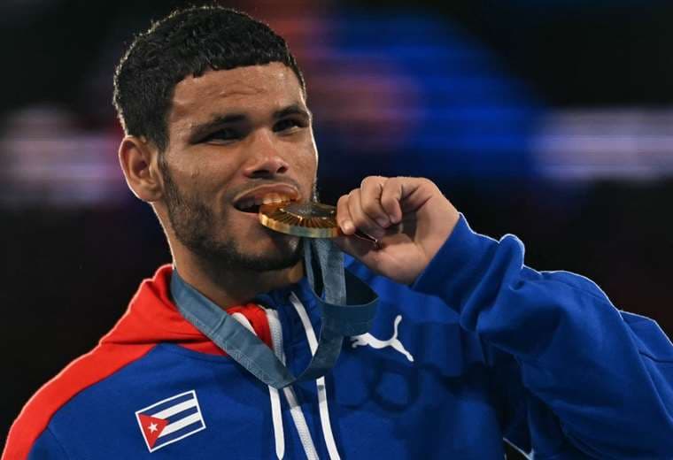 Erislandy Álvarez muerde la medalla de oro que ganó en París 2024. Foto: AFP 