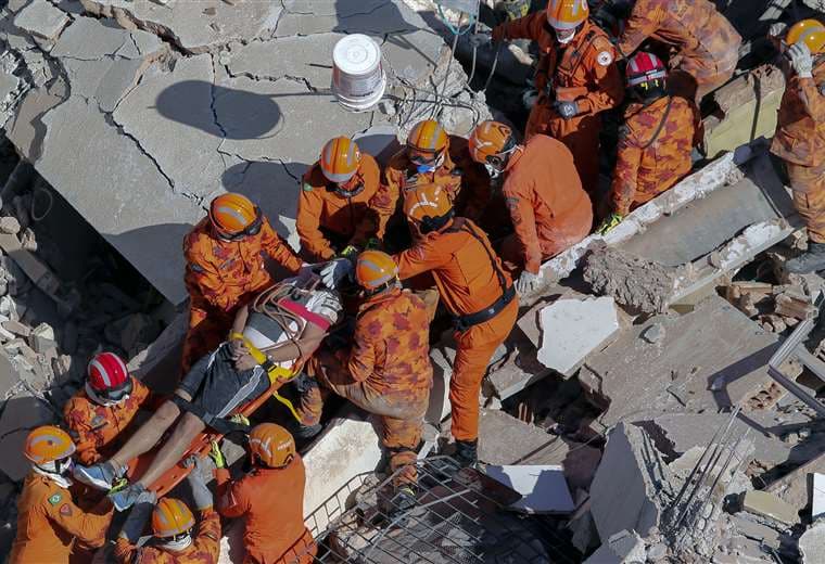 Los bomberos rescatan a un sobreviviente entre los escombros del edificio residencial. Foto AFP