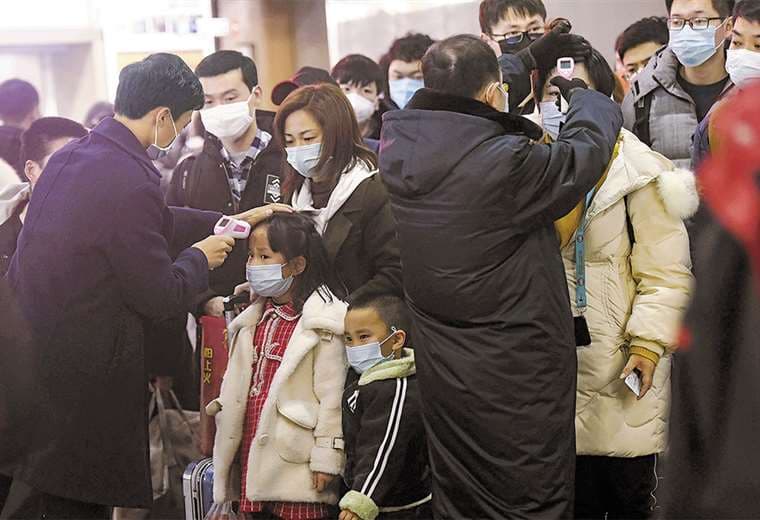 Paramédicos de la ciudad de Wuhan controlan la temperatura de personas en un centro comercial. Foto: AFP