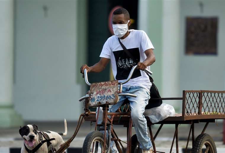 Un hombre con mascarilla en su triciclo por el centro de La Habana. Foto AFP