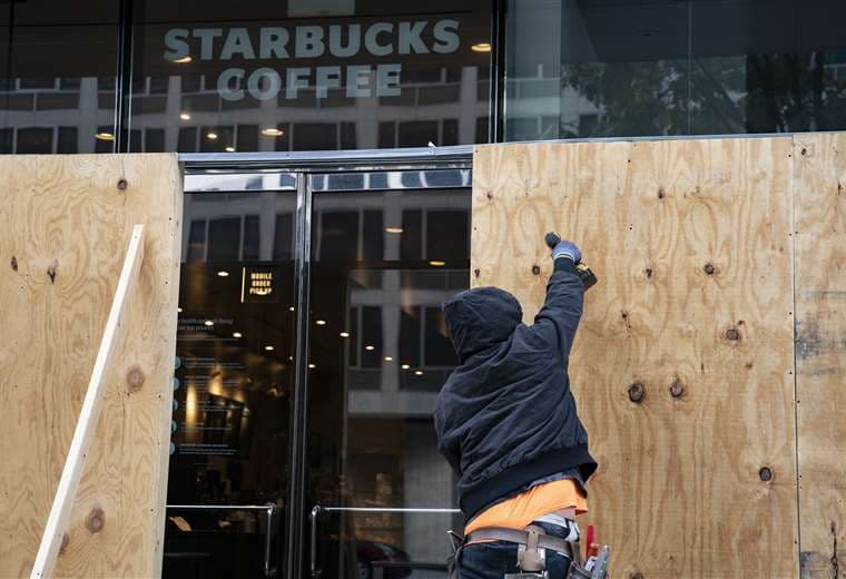 Un hombre protege con tablones un Starbucks en Washington. Foto AFP