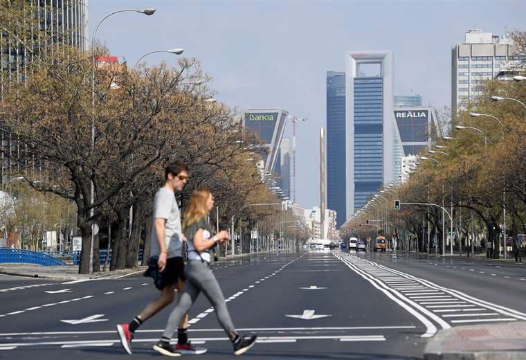 El 15 de marzo de 2020 dos personas cruzan la otrora ajetreada avenida La Castellana en Madrid, ahora vacía por el estado de alarma decretado por el gobierno debido al coronavirus que ya se ha cobrado 288 vidas en España  | Foto: AFP