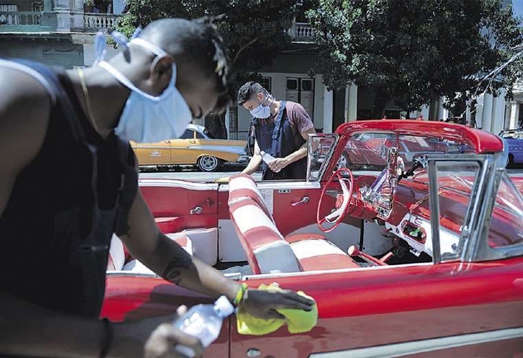 Dionis Díaz limpia su Chevrolet del 54, mientras espera turistas