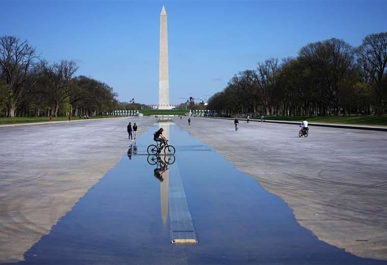 Un ciclista pasa sobre el agua en la zona de Reflecting Pool en Washington, casi desierto por la pandemia de coronavirus
