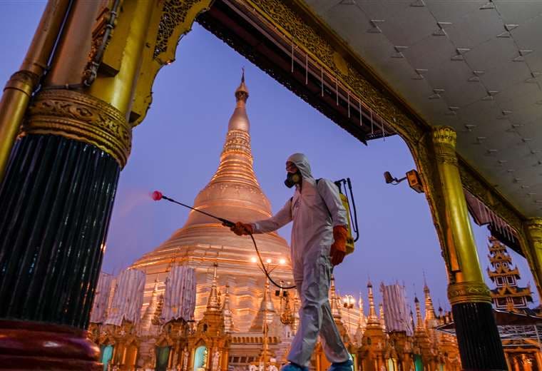 Un voluntario rocía desinfectante en los alrededores de la pagoda de Shwedagon (Miammar). Foto AFP