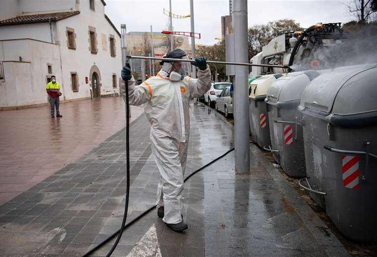 Un empleado de la municipalidad desinfecta contenedores de basura en una céntrica calle de Barcelona. Foto AFP