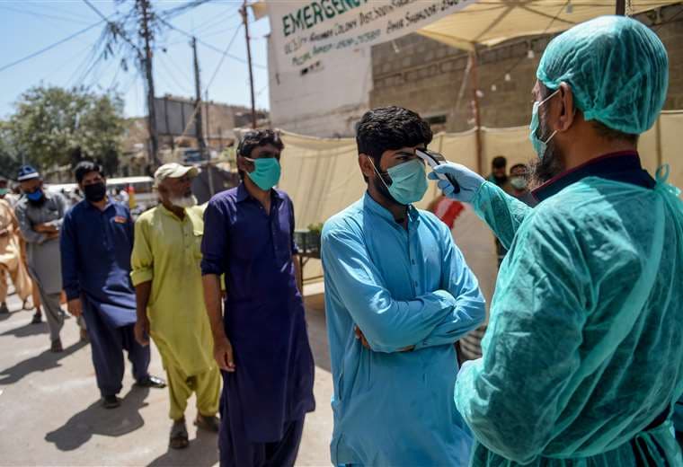 Sanitarios toman la temperatura en un barrio de Karachi. Foto AFP