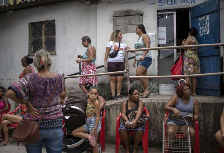 Habitantes de la favela hacen cola para recibir donativos de una ONG. Foto AFP