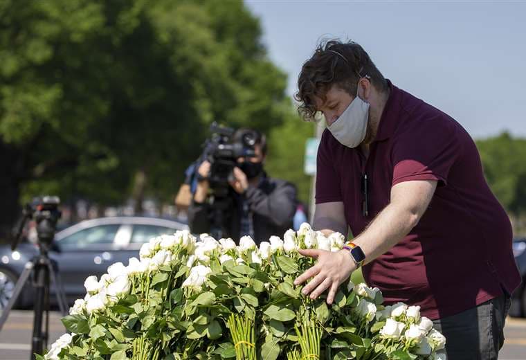 Un hombre amontona flores blancas en la Explanada Nacional de Washington en homenaje a los muertos por coronavirus. Foto AFP