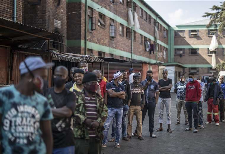 Hombres se alinean para que le hagan la prueba del Covid-19 en un albergue de Johannesburgo (Sudáfrica). Foto AFP
