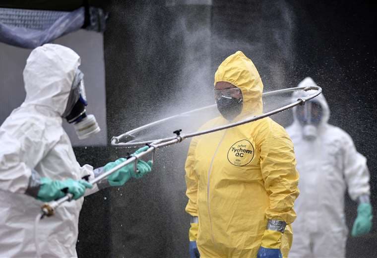 Miembros de Defensa Civil se desinfectan mutuamente luego de limpiar una terminal en Belo Horizonte. Foto AFP