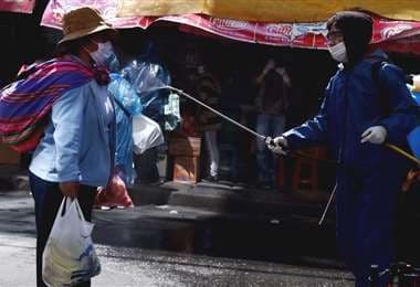Una mujer se desinfecta en una de las calles de La Paz