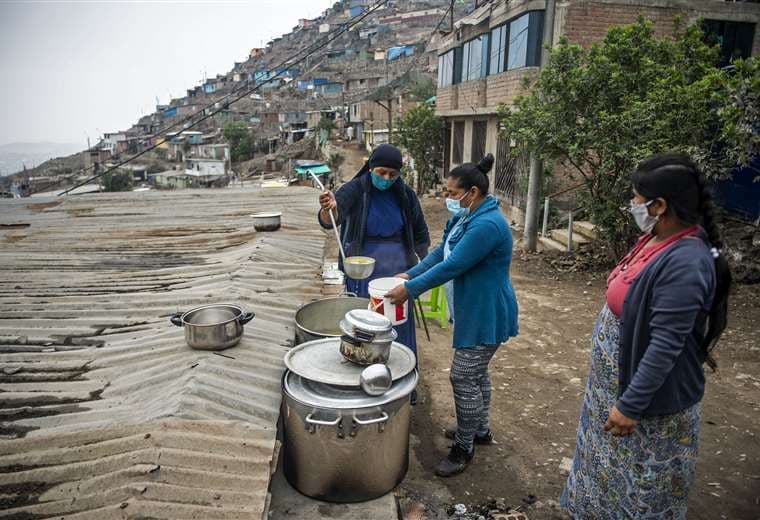 Un religiosa sirve comida de una olla común en un barrio marginal de Lima. Foto AFP