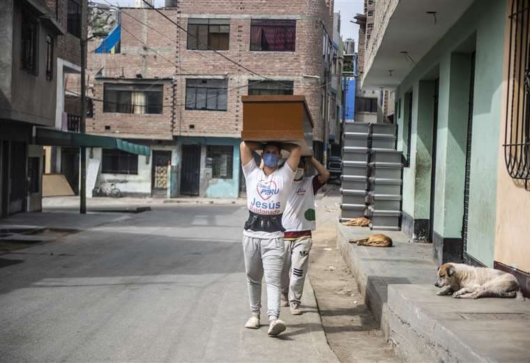 Dos trabajadores llevan un ataúd a un almacén en la región de Lurigancho en Lima. Foto AFP
