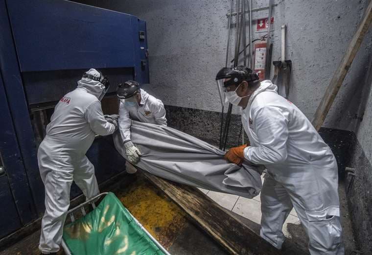 Empleados colocan el cuerpo de un fallecido por Covid en un crematorio de la Ciudad de México. Foto AFP