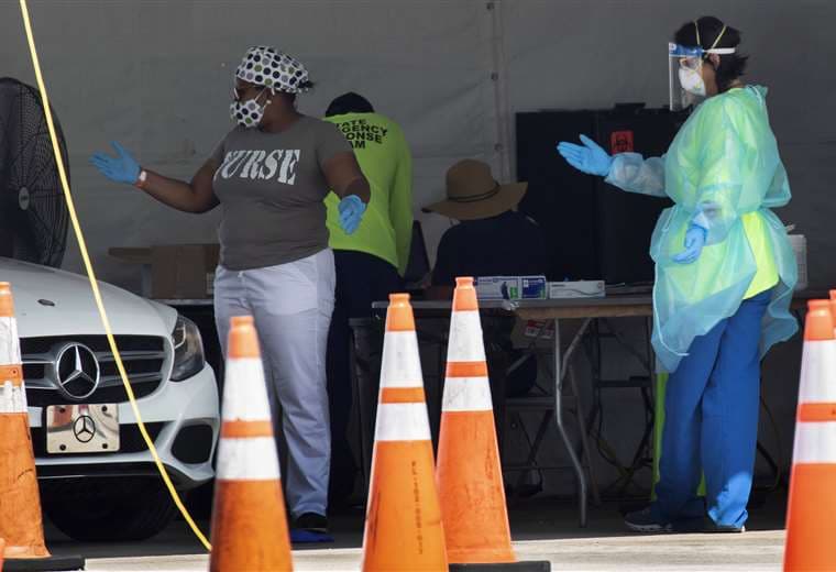 Trabajadores de salud dirigen al conductos de un vehículo en un sitio de control de Covid-19 en Florida. Foto AFP