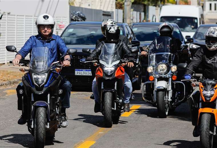 Bolsonaro (izq.) paseando en moto en Brasilia. Foto AFP