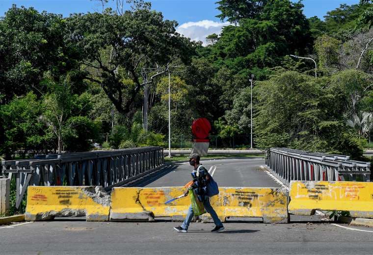 Un peatón pasa junto a una barricada colocada en un puente al sur de Caracas. Foto AFP