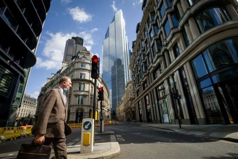 Un hombre cruza una calle desierta en la City londinense. Foto AFP