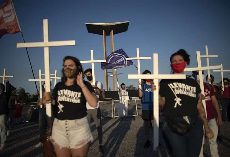 La gente sostiene cruces como homenaje a las víctimas de Covid-19 y como protesta contra la forma en que el presidente Jair Bolsonaro está manejando la pandemia. Foto AFP