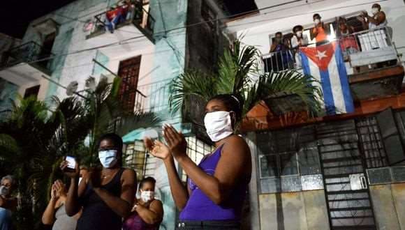 Vecinos aplauden en reconocimiento a los médicos y enfermeras que luchan contra el nuevo coronavirus en La Habana. Foto AFP.