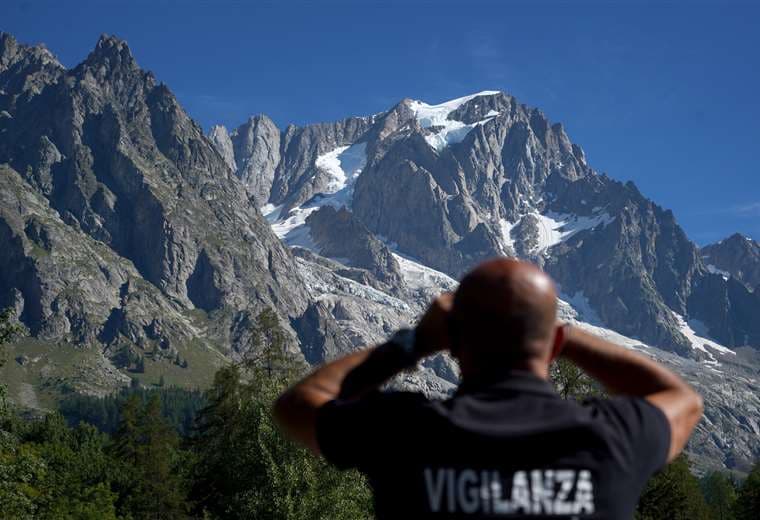 Un oficial de seguridad mira a través de binoculares el glaciar Planpincieux en la aldea de Courmayeur, Val Ferret, noroeste de Italia. Foto AFP