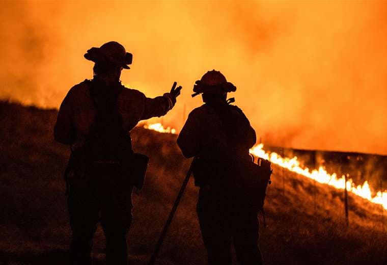 Dos bomberos observan las llamas cerca de Santa Rosa. Foto AFP