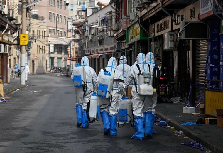 Trabajadores de salud se preparan para rociar desinfectante en un área de Shanghai | AFP