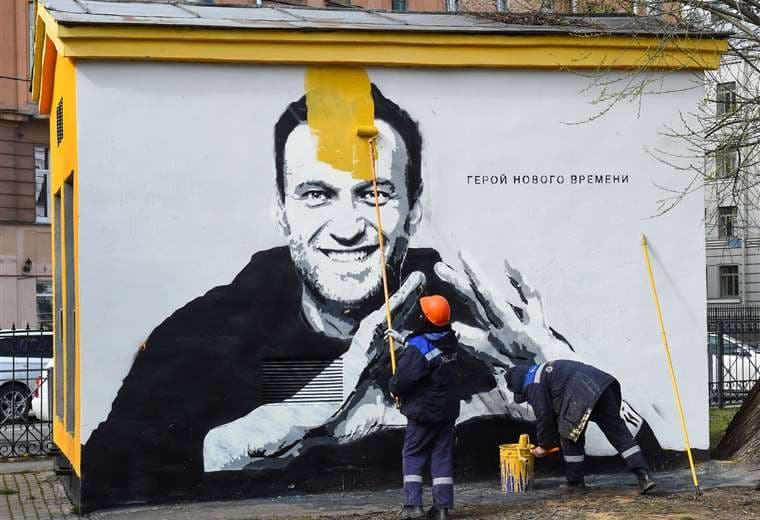 Un trabajador cubre una pintura dedicada a Navalni. Foto AFP 