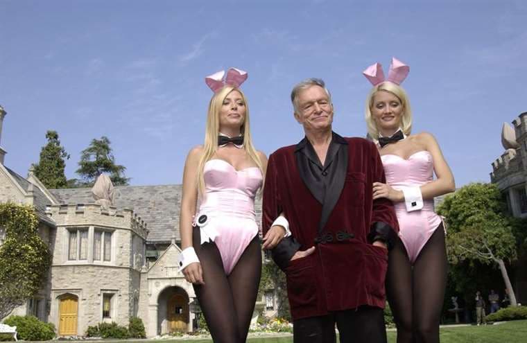 Kendra Wilkinson y Holly Madison junto a Hugh Hefner, con la mansión Playboy de fondo (Get