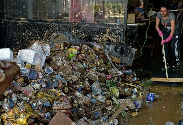 Una mujer intenta limpiar un almacén invadido por el agua en Petrópolis/ Foto: AFP