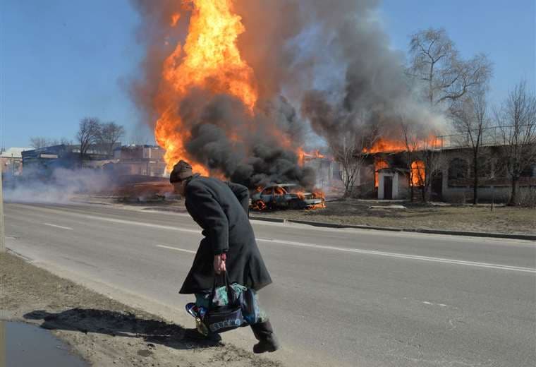 Un anciano camina mientras el fuego envuelve una gasolinera en  Kharkiv/Foto: AFP 