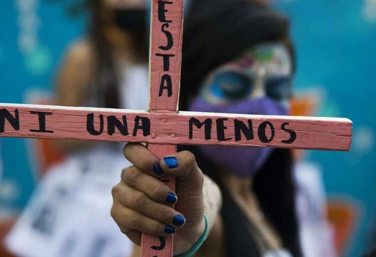 Una mujer sostiene una cruz en la que se lee "Ni una menos"/ AFP