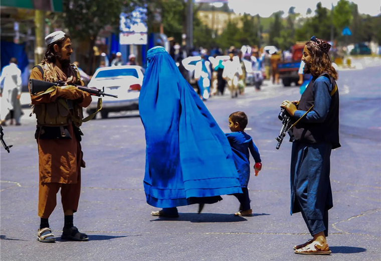 Dos talibanes observan a una mujer que camina con un niño. Foto. Internet 