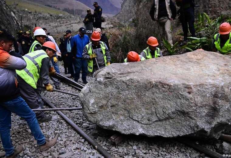 Trabajadores intentan retirar una roca colocada por manifestantes en la vía férrea.
