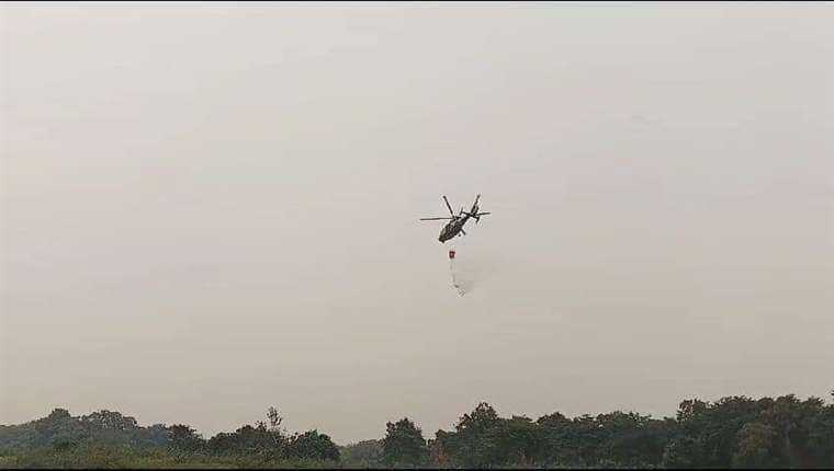 Un helicóptero de la FAB sobrevuela y descarga agua para mitigar los incendios